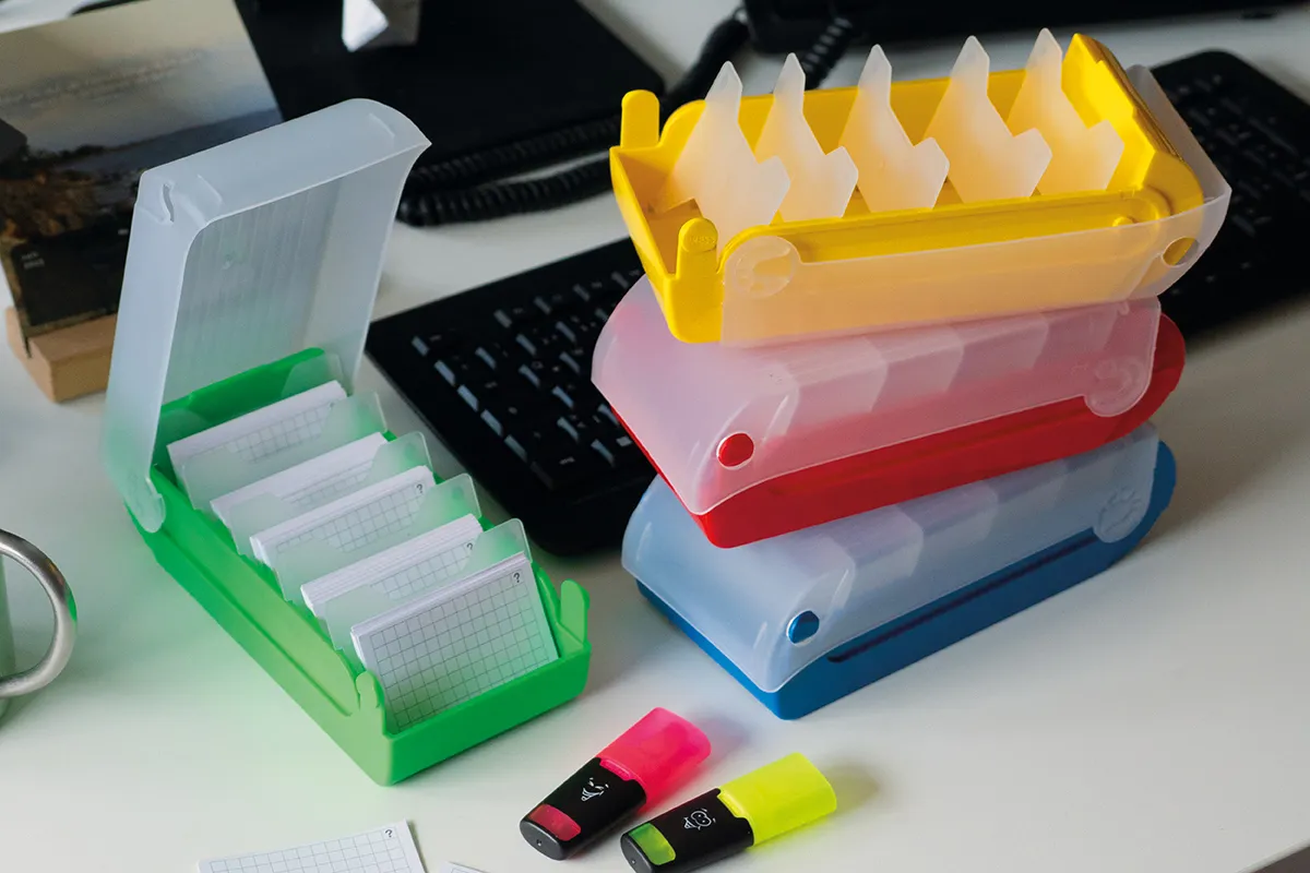 Auf einen Schreibtisch liegen Karteikartenboxen in unterschiedlichen Farben. Daneben liegen 2 Mini-Textmarker